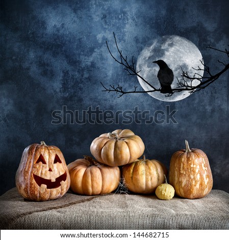 Halloween pumpkins and crow on the branch at full moon and textured dark background