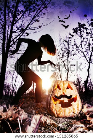 Halloween pumpkin with moustache and silhouette of witch in the dark forest