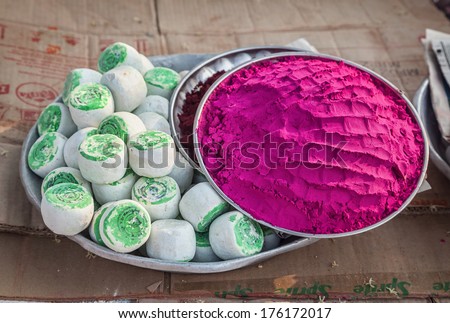 HAMPI, KARNATAKA, INDIA - MARCH 11, 2013: Pink paint powder in the bowl on cardboard at Hampi bazaar.