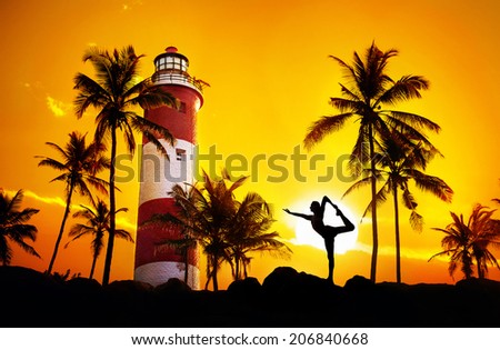 Man doing Yoga dancer pose in silhouette near lighthouse at sunset sky in Kovalam, Kerala, India
