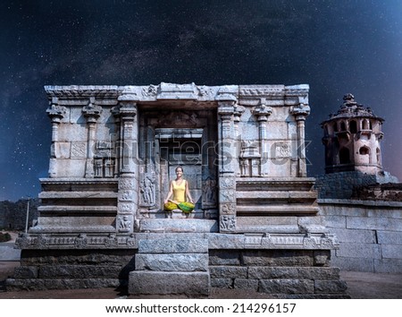 Woman doing meditation in ruined temple at night sky with Milky Way in Hampi, Karnataka, India