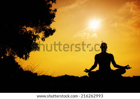 Man silhouette in Yoga meditation pose near the tree at sunset in Gokarna, Karnataka, India