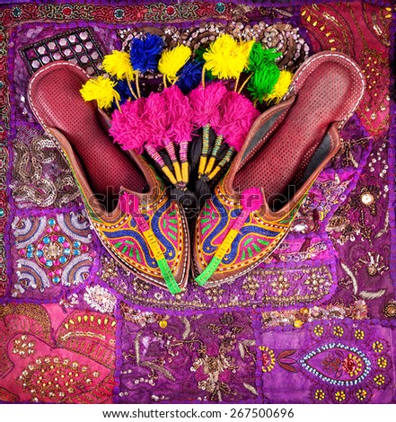 Colorful ethnic shoes and camel decorations on violet Rajasthan cushion cover on flea market in India