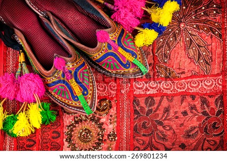 Colorful ethnic shoes and camel decorations on red Rajasthan cushion cover on flea market in India