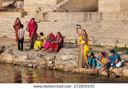 JAISALMER, RAJASTHAN, INDIA - MARCH 13, 2015: Women in colorful saris doing pooja religious ritual near Gadi Sagar saint lake