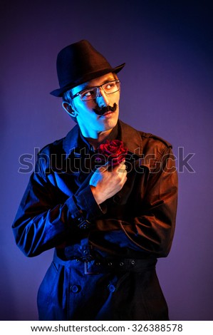 Man in black hat with red rose waiting for somebody at dark background