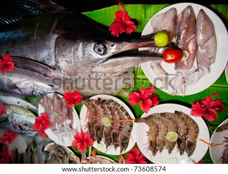 Different raw fish, calamari and prawns in flowers on banana leaf on street market in India