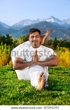 Yoga meditation eka pada shirshasana foot behind the head pose by concentrate Indian Man in white cloth in the morning at mountain and blue sky background. Free space for text