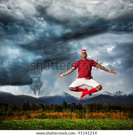 Flying Indian man in meditation in Christmas hat at Hurricane and dramatic sky background. Represent negotiation of your inner fears