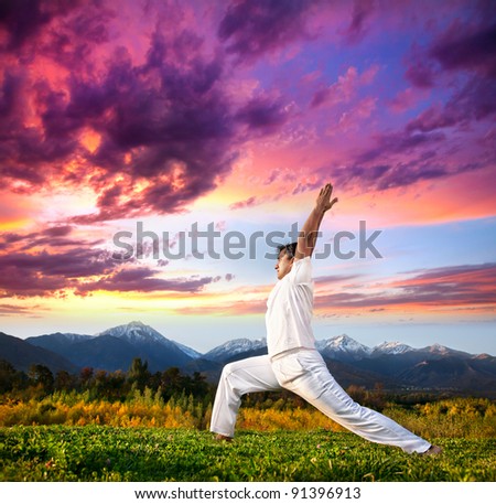 Yoga virabhadrasana I warrior pose by Indian Man in white cloth in the morning at mountain background
