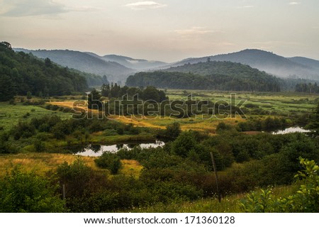 Late summer in the Adirondack Mountains in New York with a swampy foreground and fog in the background mountains.