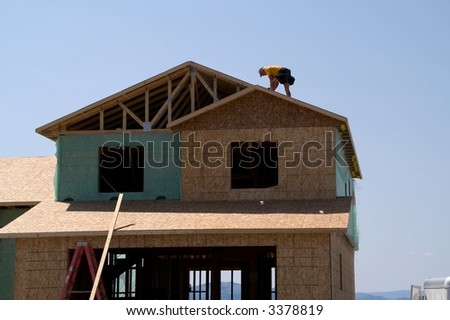Construction worker  on roof of a new home with mountains in the background