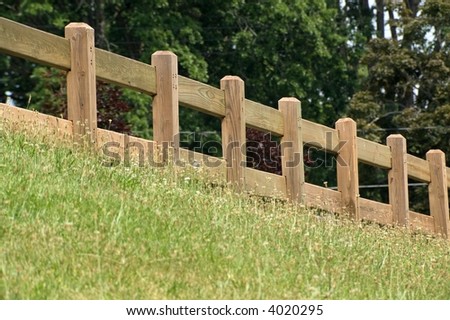 Wooden fence providing protection  from the hill for a walking path