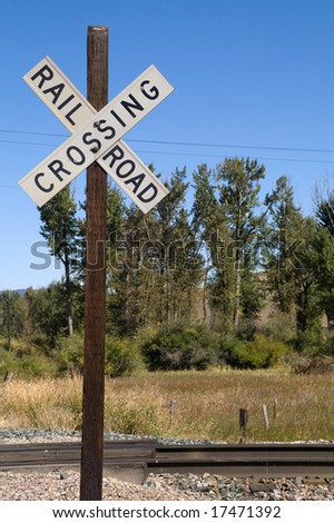 Railroad crossing sign on wooden post next to the track
