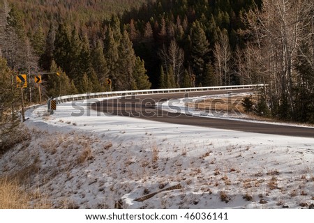 Mountain road with light snow in the fall.  Pine trees have been partially wiped out by pine beetles.