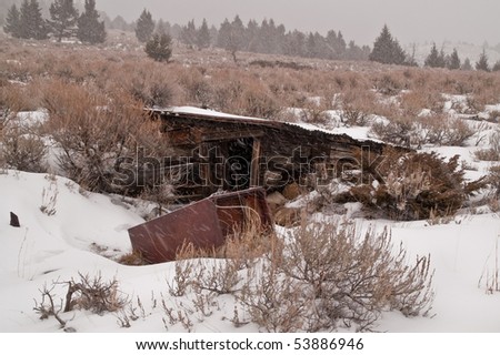 Dilapidated building in a Montana ghost town may have housed the spring that provided water for the town.  A rusty refrigerator sits in the foreground.