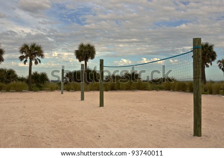 Volleyball sand courts under a partly cloudy sky with the ocean in the background
