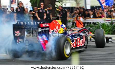 SINGAPORE - APRIL 24: David Coulthard, performs donuts in Redbull Racing Car on the streets of Orchard Road on April 24, 2011 in Singapore.
