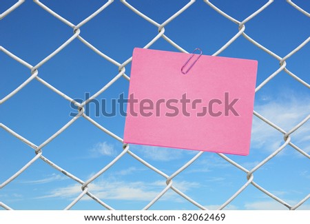 pink note on chain link fence see blue sky