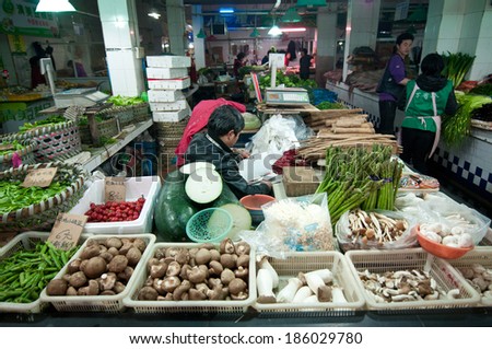 SHANGHAI, CHINA - MARCH 22: vegetables seller reads book on his food stand at food market on Old City of Shanghai (Nanshi) on March 22, 2013 in Shanghai
