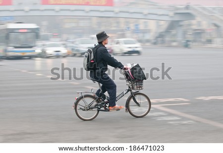 BEIJING, CHINA - MARCH 31: young man rides bike on a busy street in Dongcheng District on March 31, 2013 in Beijing