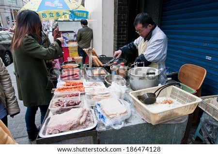SHANGHAI, CHINA - MARCH 21: Chinese man sells food snacks on a food stand on March 21, 2013 in Shanghai