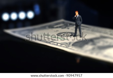 tiny figure of businessman standing on one dollar bill