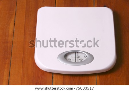 White bathroom scale placed on wood floor