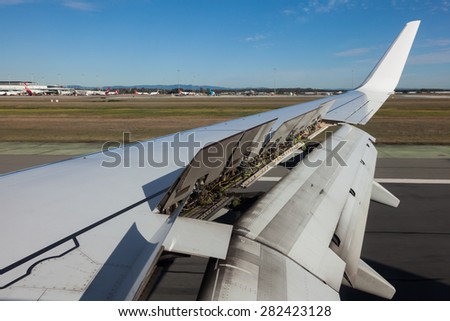An airplane window view of wing and flaps after landing.