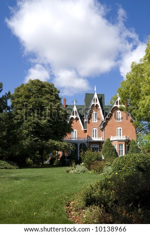 An ornate, nineteenth-century North American red brick house in late summer.