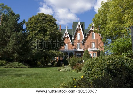 An ornate, nineteenth-century North American red brick house in late summer.