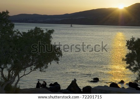 Sunset over Greek sea with people on the beach