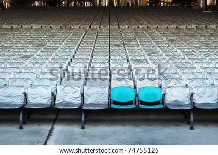 Two of blue chairs without protection material on background of many covered chairs