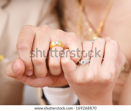 Bride and groom wear wedding rings,hook each other\'s little finger