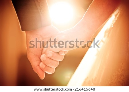 Bride and groom holding hands in wedding ceremony with sunset