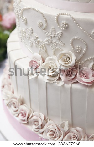 Close up white wedding cake decorate with roses and pearl