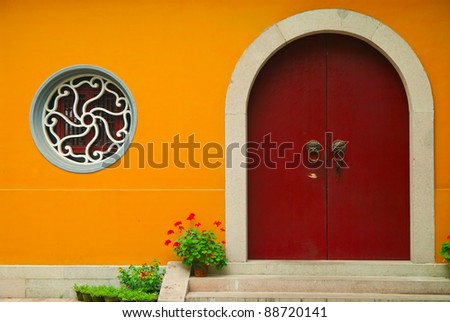 Bright orange wall facade with old door and a rounded window