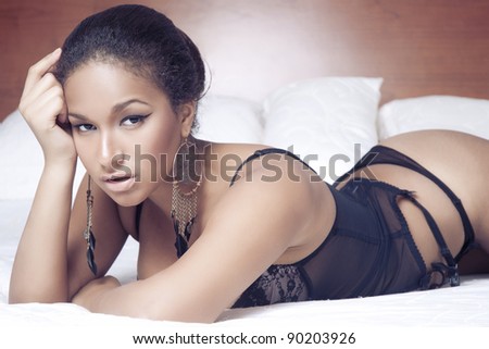 Portrait of a sensual sexy african woman lying on the bed in black lingerie