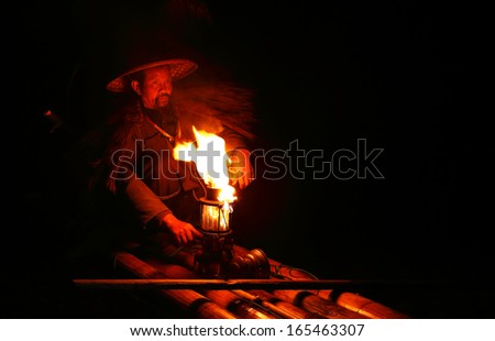 YANGSHUO - OCTOBER 16: Chinese fisherman kindles a lamp before fishing with cormorants birds in Yangshuo,  traditional fishing use trained cormorants to fish, October 16, 2013 Yangshuo, China
