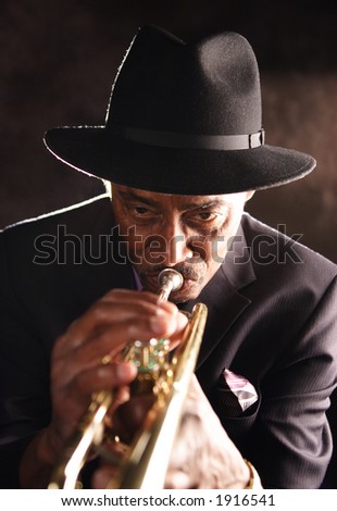 Elderly black man playing a trumpet. He has a soulful countenance.