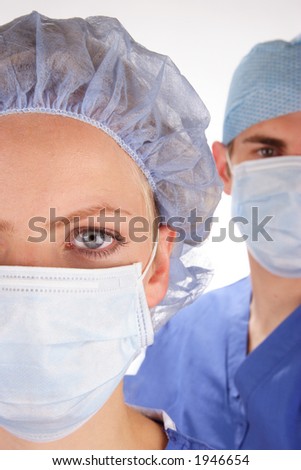 Doctor and nurse wearing surgical scrubs. Nurse in foreground. Shallow depth of field with doctor slightly out of focus in background.