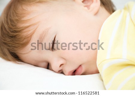 Cute little boy is sleeping on a white pillow