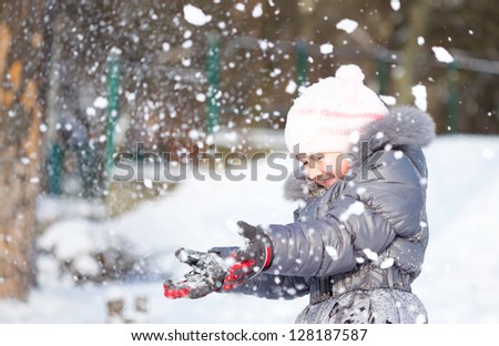 Little girl is throwing snow playing outdoors