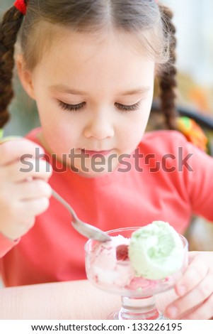 Cute little girl is eating ice-cream in parlor