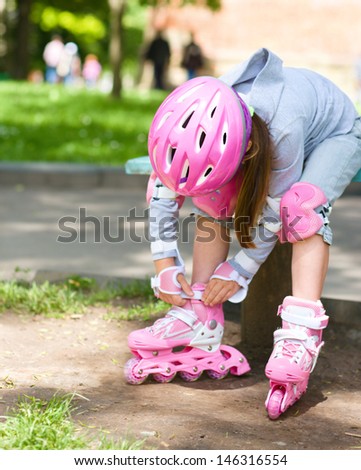 Little girl is wearing roller-blades in city park