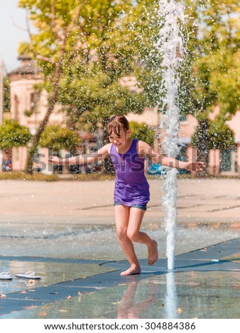 Hot summer in the city - girl is enjoying fountain with cold water