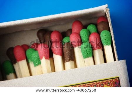 Multicolored matchsticks in the box on blue background, shallow DOF