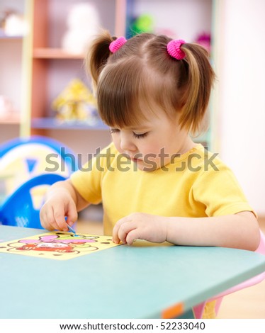 Cute little girl coloring a picture in preschool