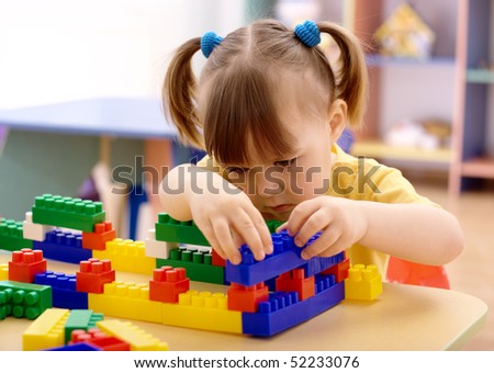Cute little girl play with building bricks in preschool