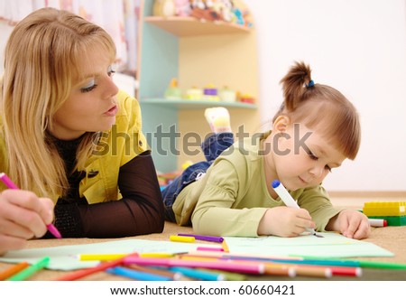 Teacher and child draw with felt-tip pens in preschool